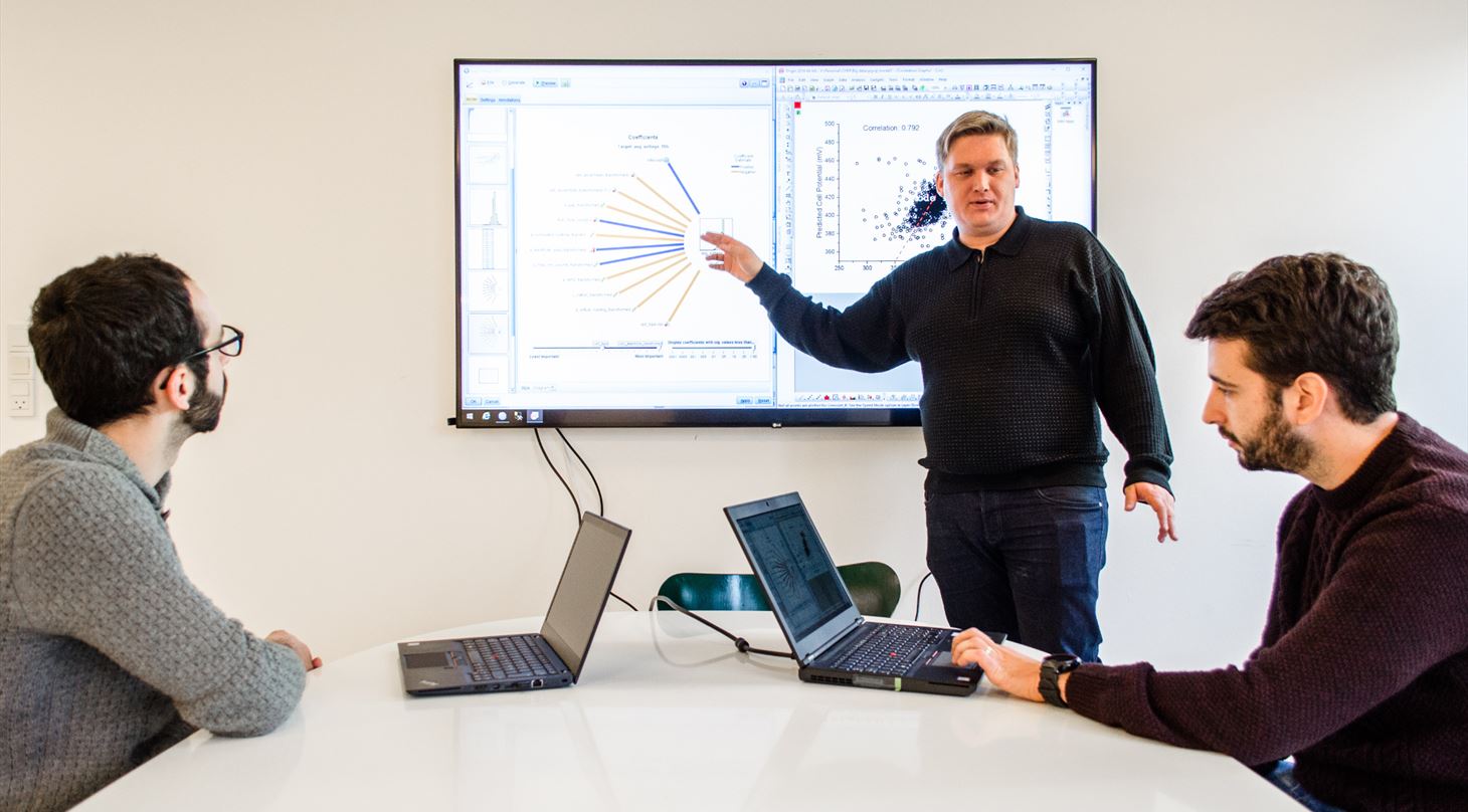 Three scientists working with Big Data on computers and a big screen